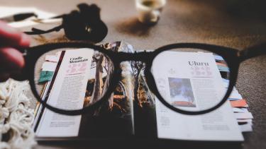 Ewan Robertson image Image of newspaper with someone holding glasses