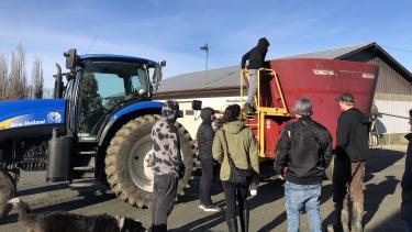 Bakerview - Lets'emo:t Program Highschool Students standing and looking at blue tractor