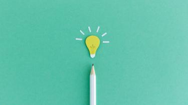 iStock Image - Creative Writing Creative composition of pencil with small paper light bulb glowing above on green background