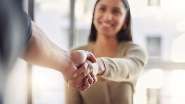 Focused image of a handshake with female blurred in background