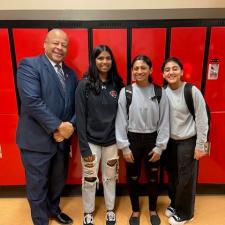 Male Superintendent poses with 3 female high school students